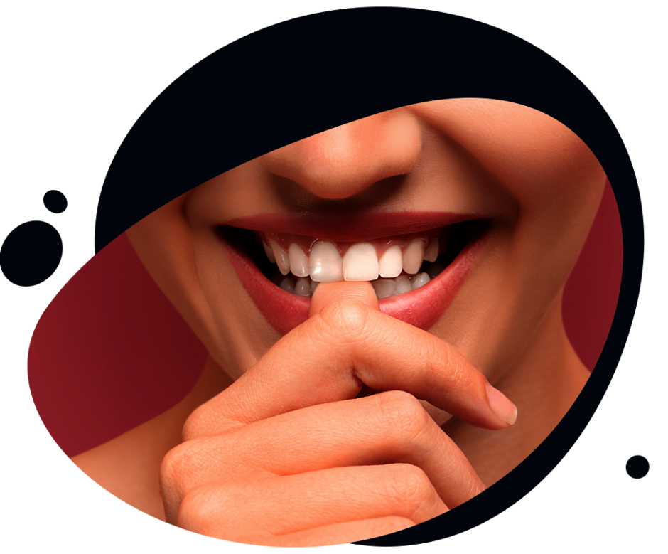 Nahaufnahme des Mundes einer Frau, die lächelt und ihren Daumen gegen die Frontzähne drückt
