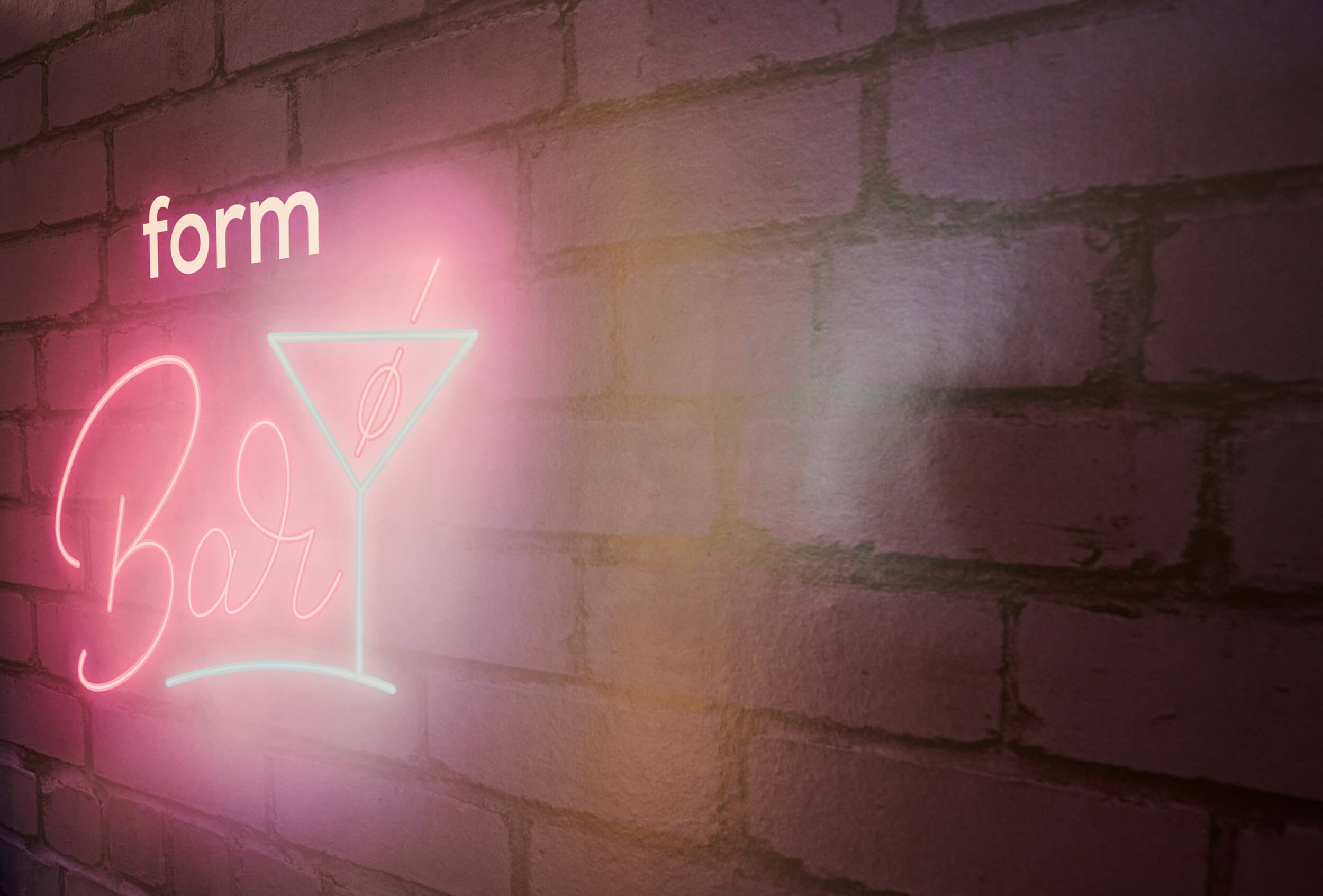 Neonschriftzug „form Bar“ an einer Backsteinwand
